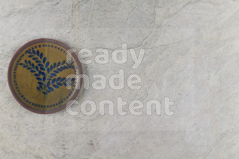 A decorative pottery plate on grey marble background