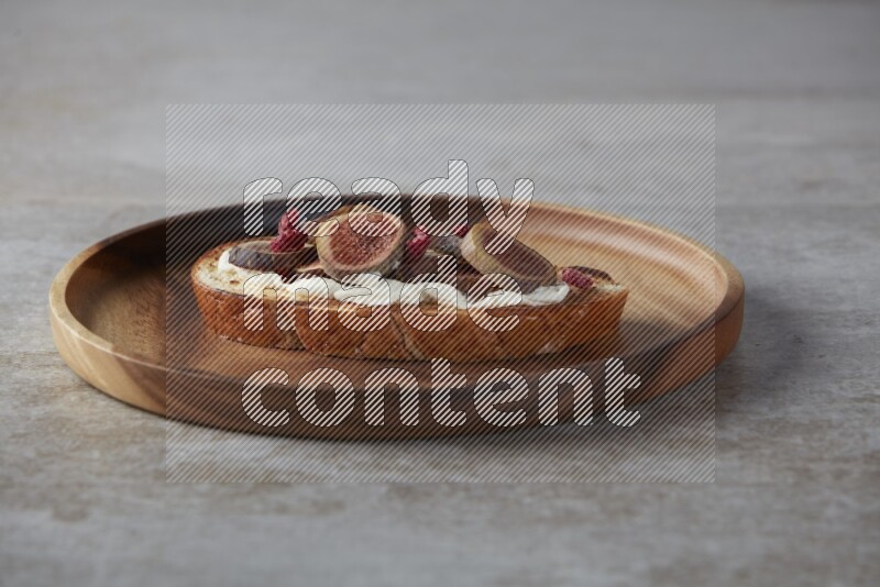 figs slices  with cream cheese on toasted sourdough slice on a wooden board on textured grey background
