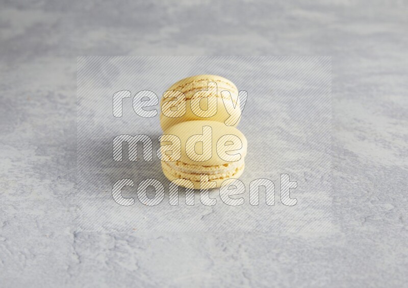 45º Shot of two Yellow Vanilla macarons  on white  marble background