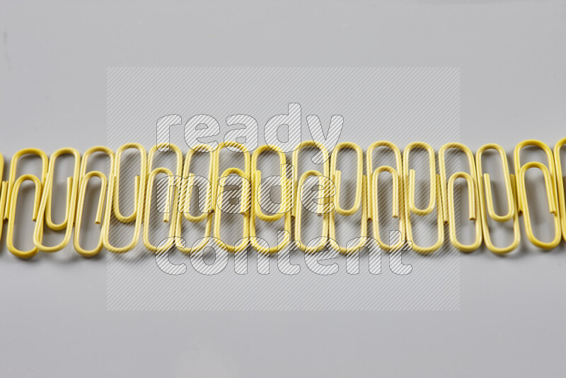 Yellow paper clips isolated on a grey background