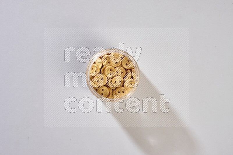 أزرار ملونة في وعاء زجاجي على خلفية رمادية