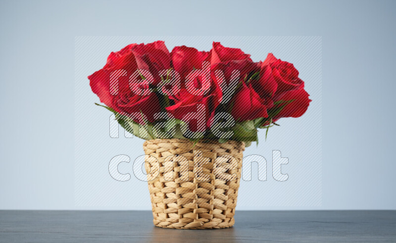 باقة من الورود الحمراء موضوعة في سلة خوص على خلفية من الرخام الأسود