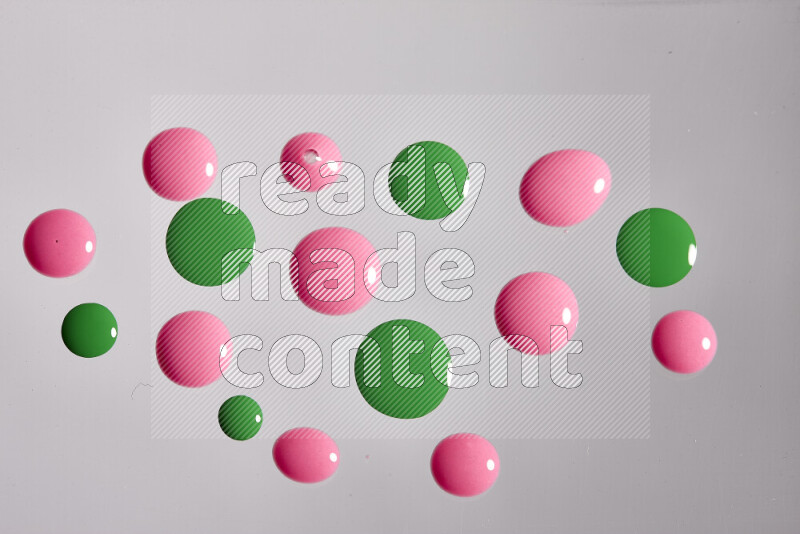 Close-ups of abstract pink and green paint droplets on the surface