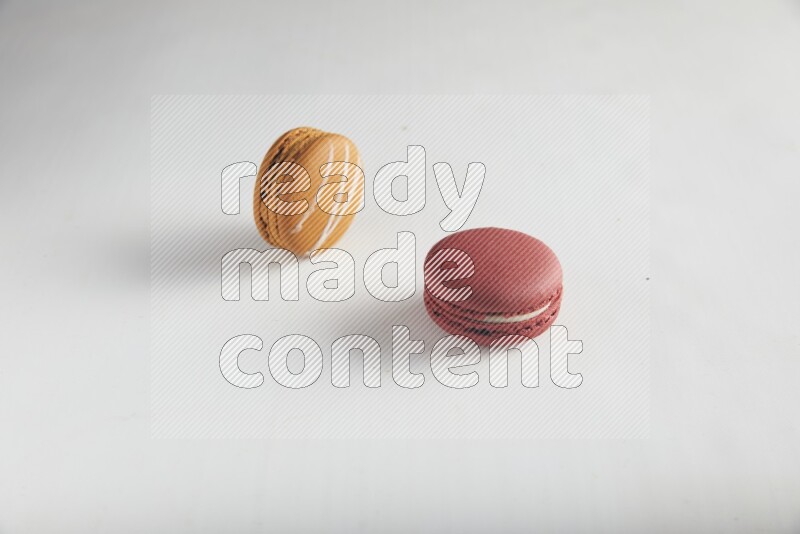45º Shot of of two assorted Brown Irish Cream, and Red Velvet macarons on white background