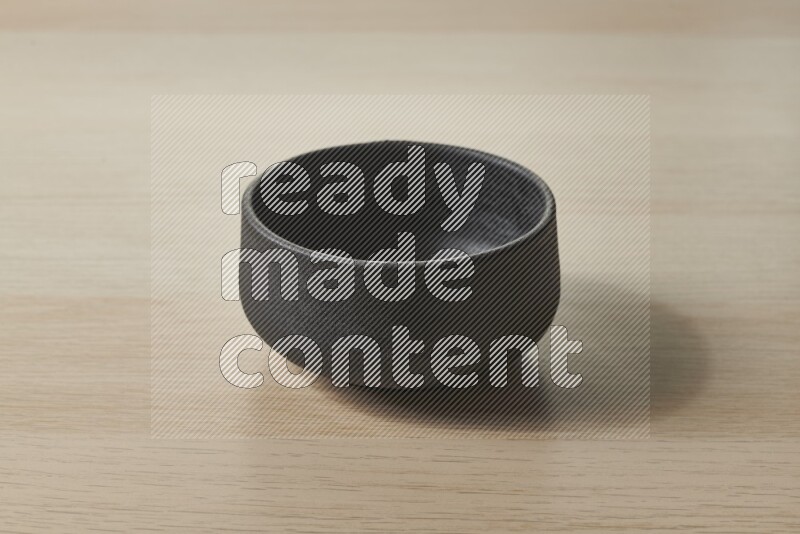 وعاء فخاري أسود على خلفية خشبية فاتحة