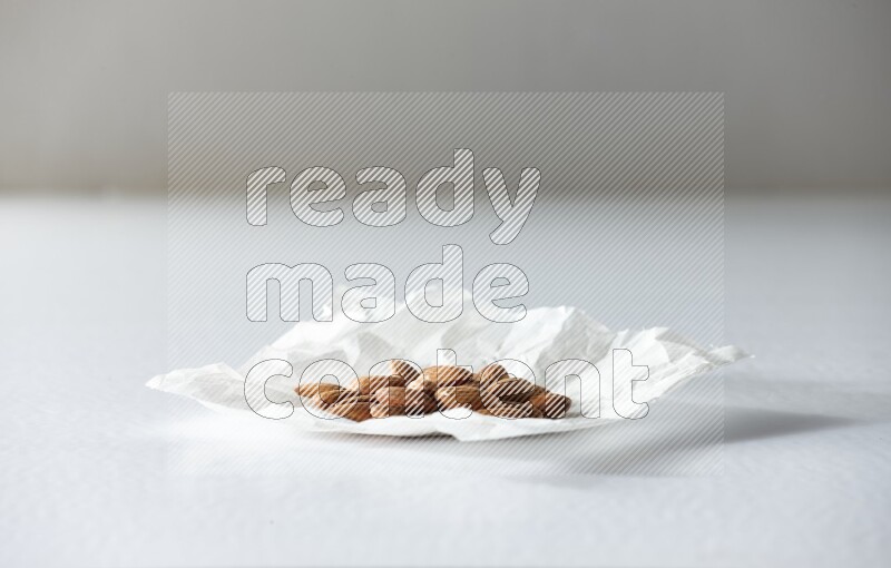 Peeled almonds on a crumpled piece of paper on a white background in different angles