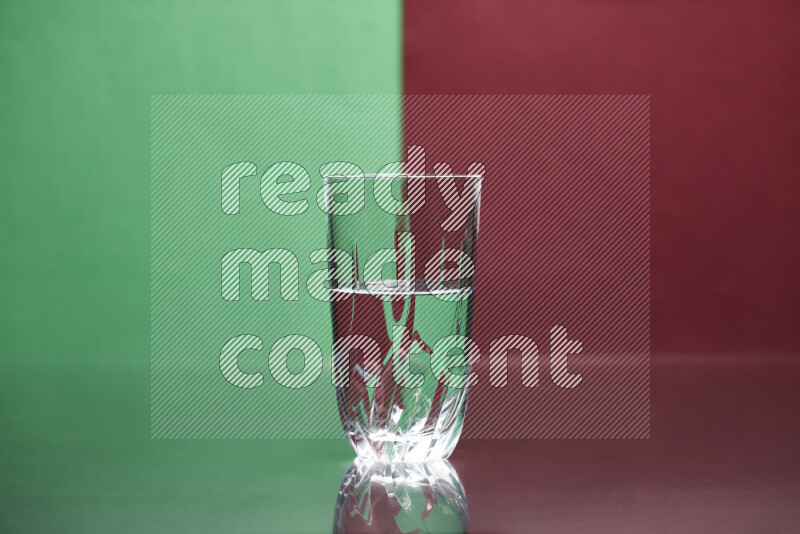 The image features a clear glassware filled with water, set against green and dark red background