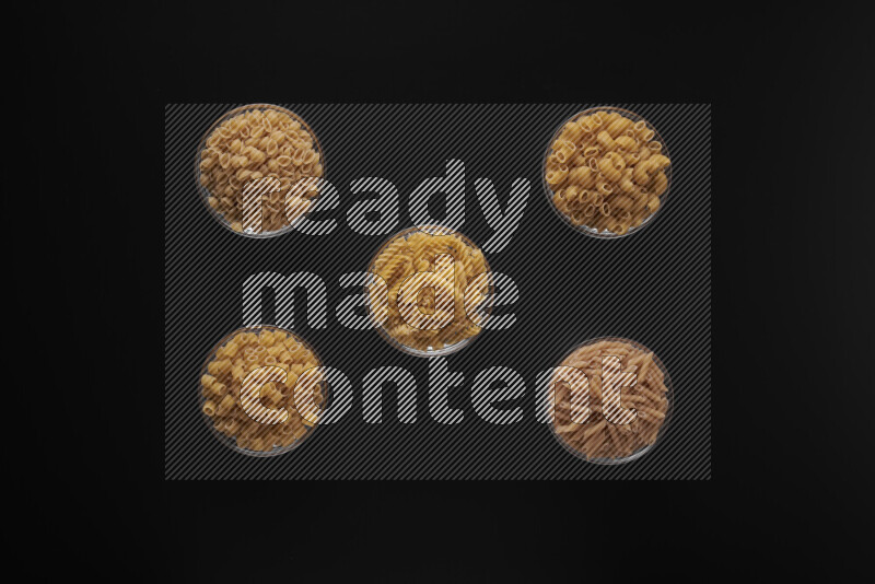 أنواع مختلفة من المعكرونة في أوعية زجاجية علي خلفية سوداء