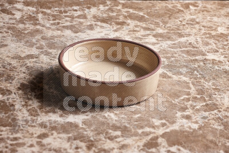 A beige pottery oven plate on beige marble background