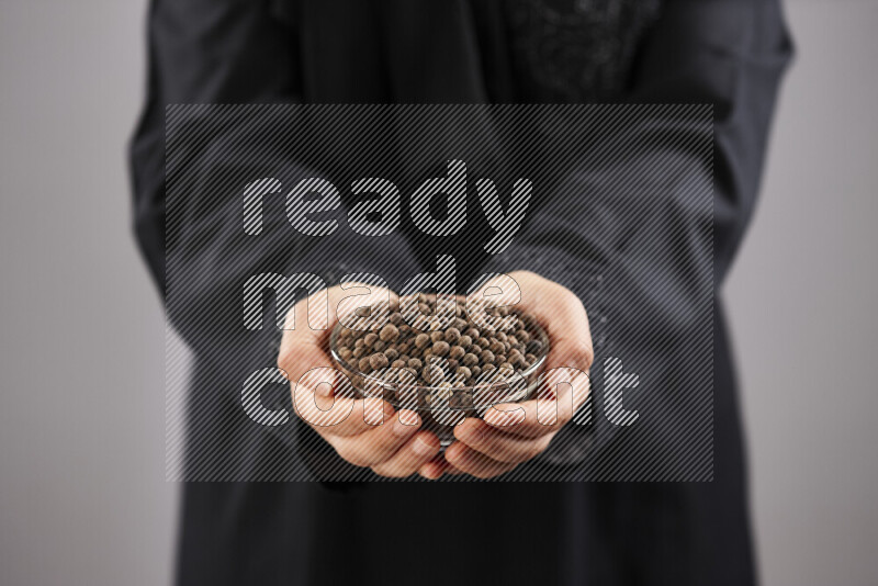 Woman in abaya holding different kinds of spices in different positions