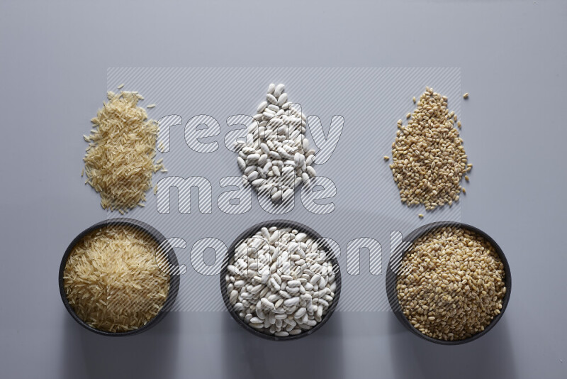 Legumes in pottery bowls on light grey background
