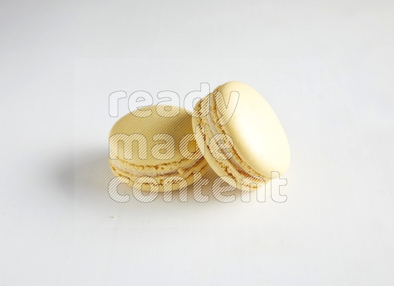 45º Shot of two Yellow Vanilla macarons on white background