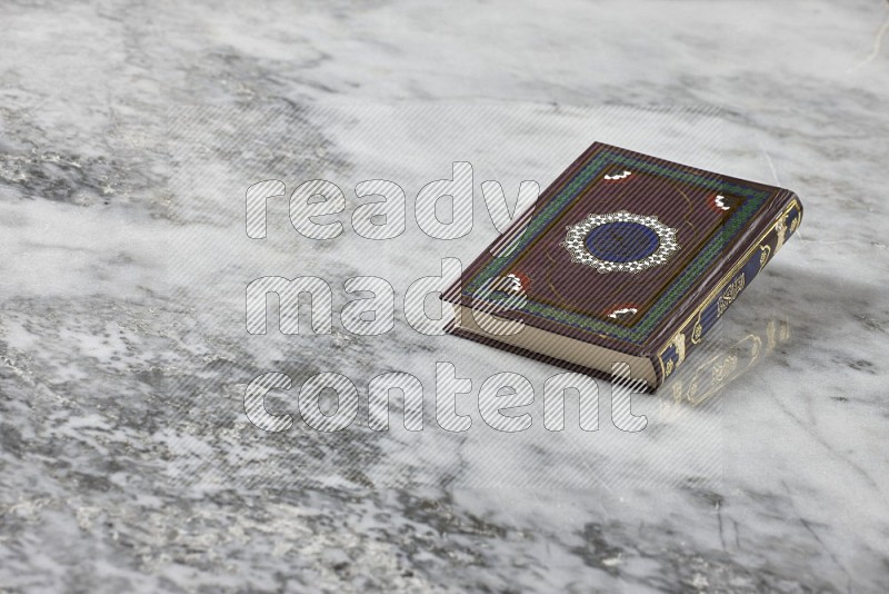 Quran with a prayer beads on grey marble background