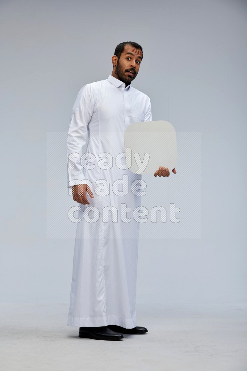 Saudi man wearing Thob standing holding social media sign on Gray background