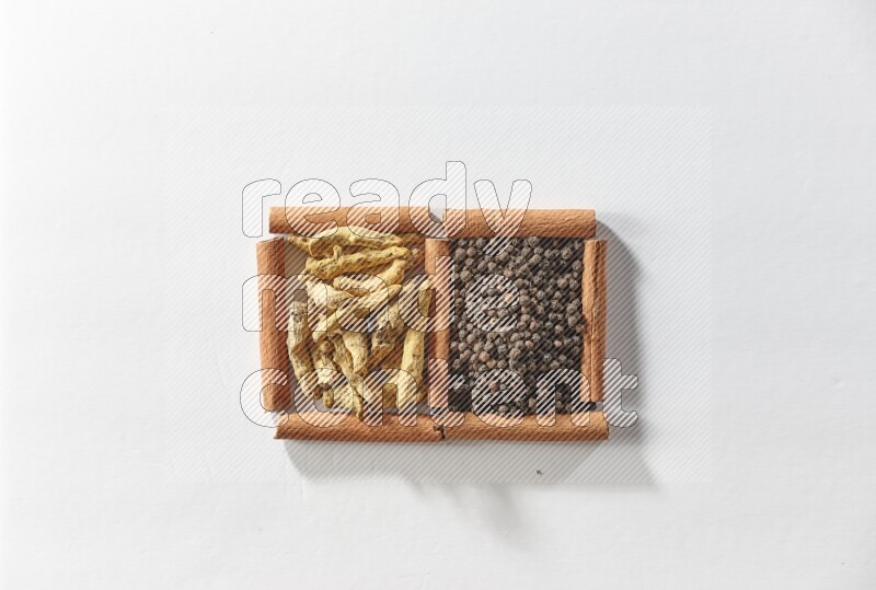 2 squares of cinnamon sticks full of black peppers and turmeric fingers on white flooring