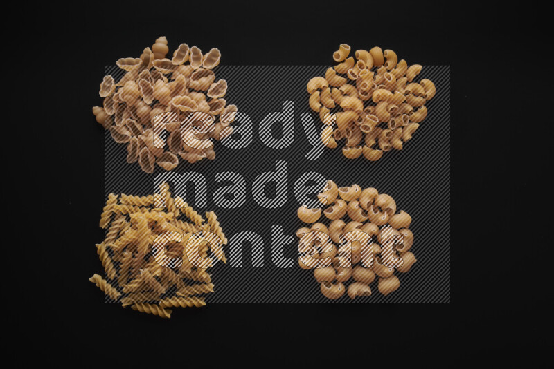 Different pasta types in bunches on black background