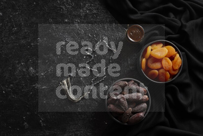 Dried fruits in pottery bowls with coffee in a dark setup
