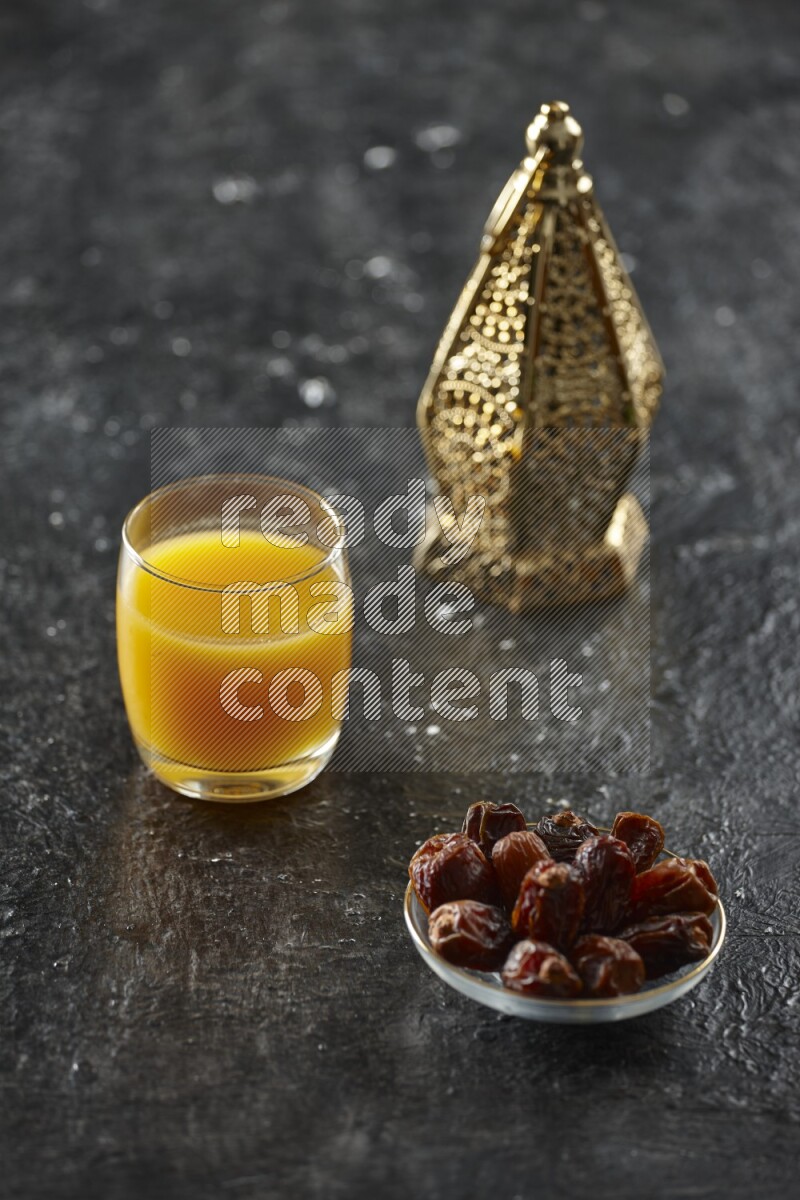 A golden lantern with different drinks, dates, nuts, prayer beads and quran on textured black background