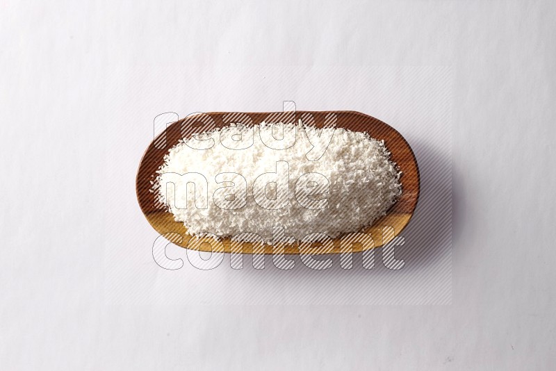 Desiccated coconuts in a wooden plate on white background