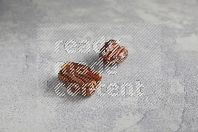TWO pecan stuffed dates on alight grey background