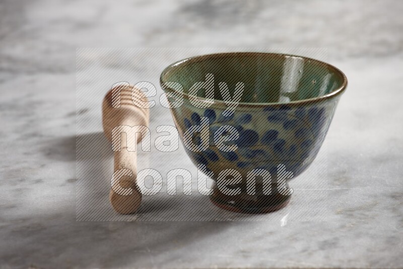 Decorative pottery bowl with wooden honey dipper on the side on grey marble background