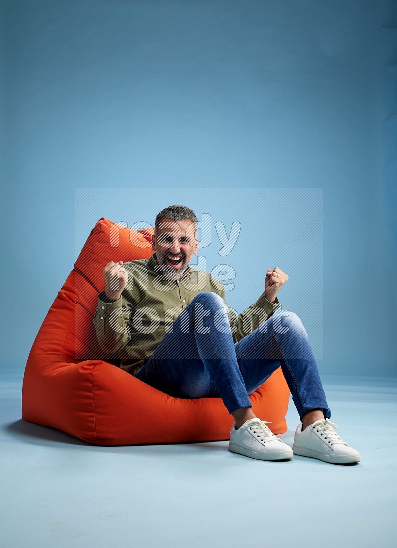 A man sitting on an orange beanbag and interacting with the camera