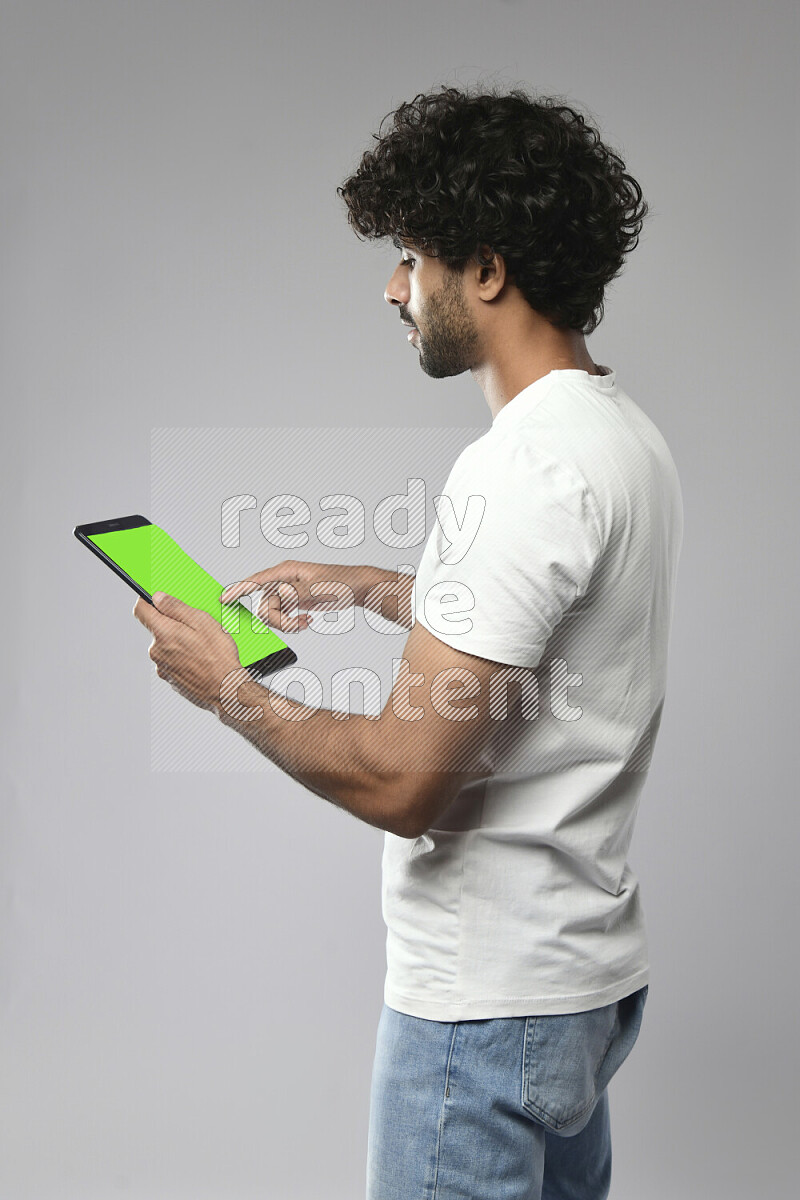 A man wearing casual standing and browsing on a tablet on white background