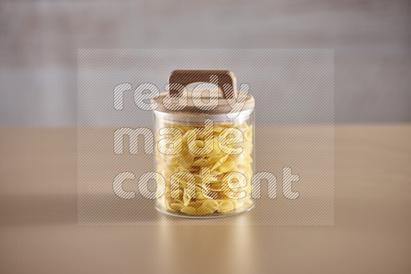 Raw pasta in glass jars on beige background