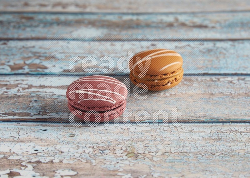 45º Shot of of two assorted Brown Irish Cream, and Red Poppy Flower macarons  on light blue background