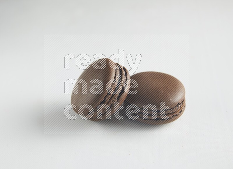 45º Shot of two Brown Dark Chocolate macarons on white background