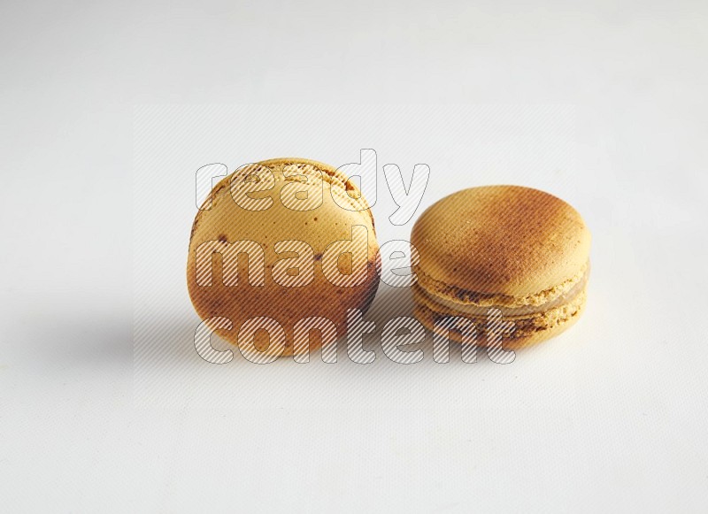 45º Shot of two Yellow Crème Brulée macarons on white background