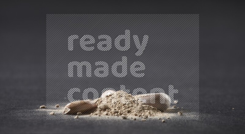 كومة صغيرة من بودرة الثوم مع بعض فصوص الثوم ورأس ثوم كاملة على خلفية سوداء