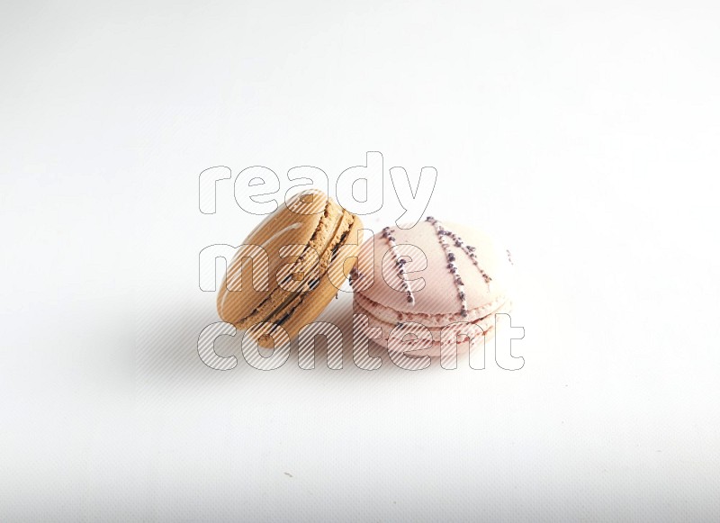 45º Shot of of two assorted Brown Irish Cream, and pink orange blossom macarons on white background