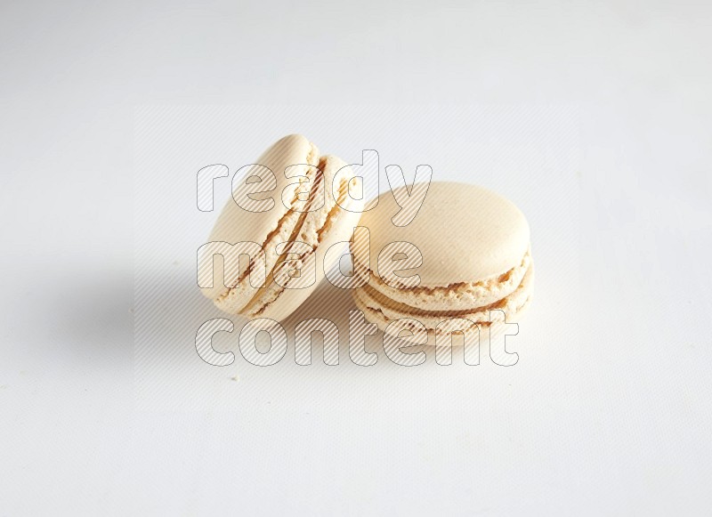 45º Shot of two White Caramel fleur de sel macarons on white background