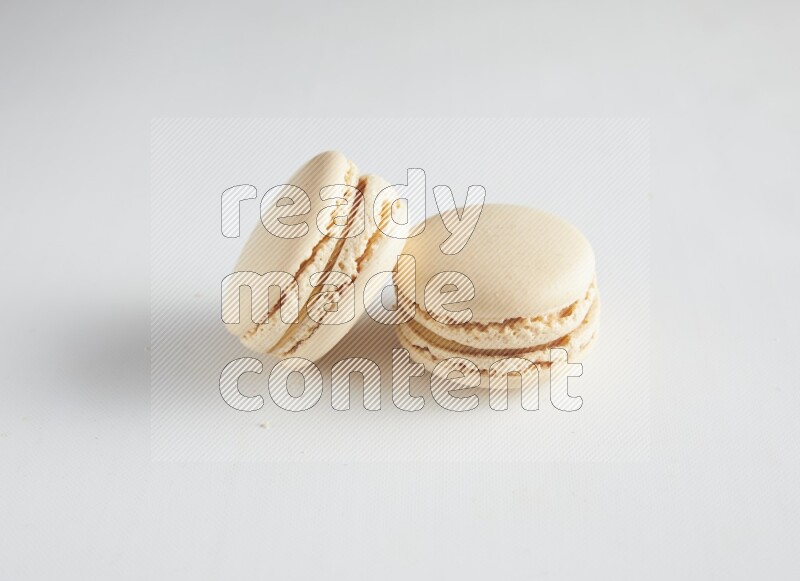 45º Shot of two White Caramel fleur de sel macarons on white background
