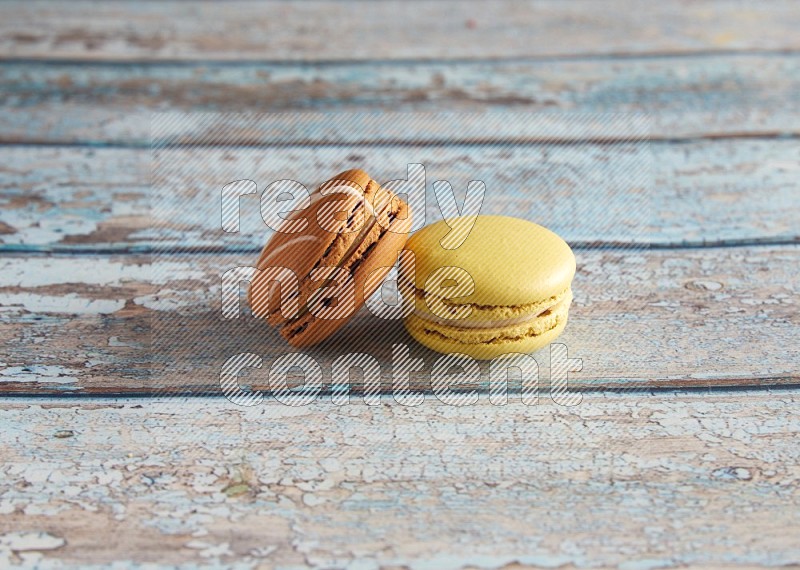 45º Shot of of two assorted Brown Irish Cream, and Yellow Lime macarons on light blue background