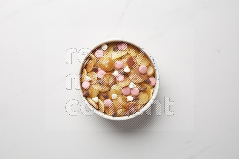 Top-view shot of mixed chocolate chips cereal pancakes in a round bowl on white background
