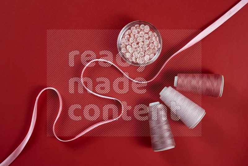 Pink sewing supplies on red background