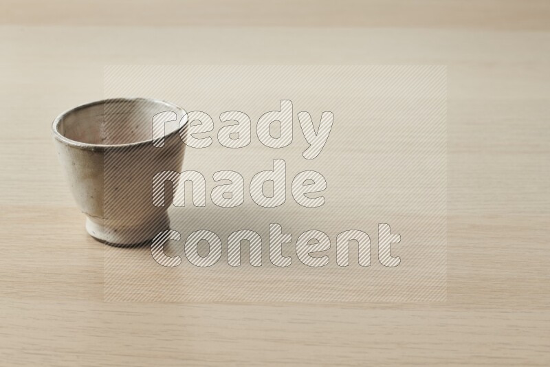 A pottery cup on light wooden background