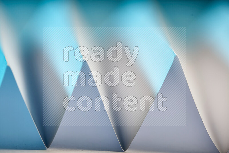 A close-up abstract image showing sharp geometric paper folds in white and blue gradients