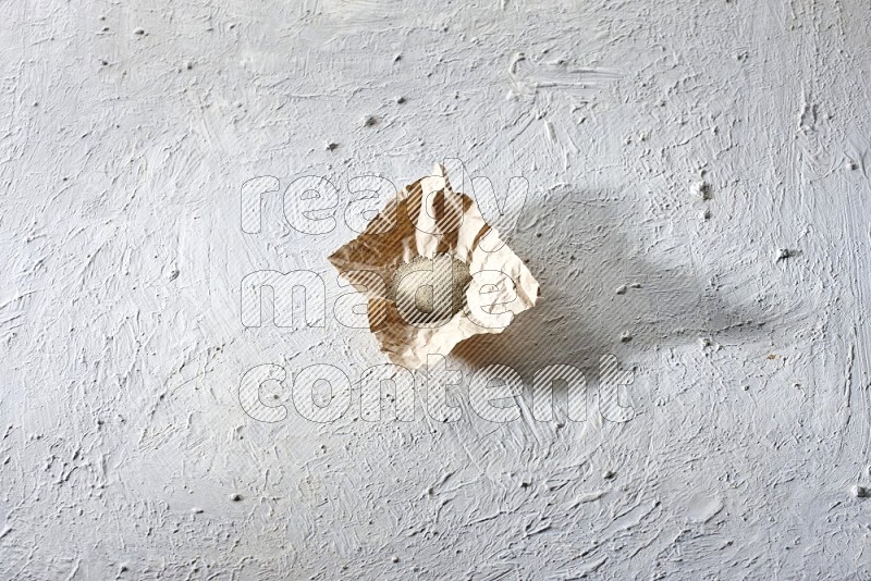 White pepper powder in a crumpled piece of paper on textured white flooring