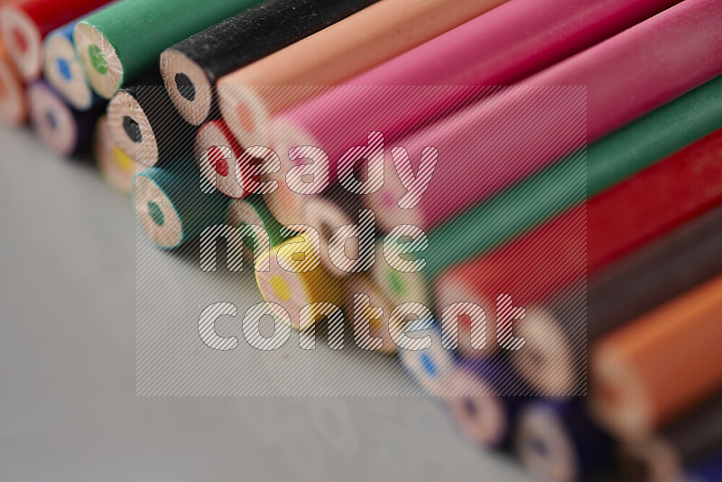 An array of colored pencils on grey background