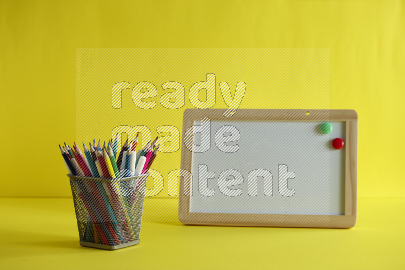 A whiteboard with different school supplies on yellow background
