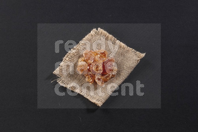 Gum arabic on a burlap piece on black flooring in different angles