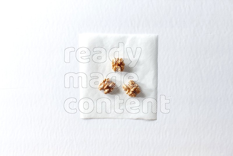 3 peeled walnuts on a piece of paper on a white background in different angles