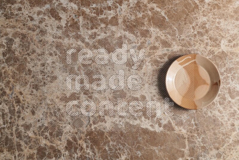 A multicolored pottery plate on beige marble background