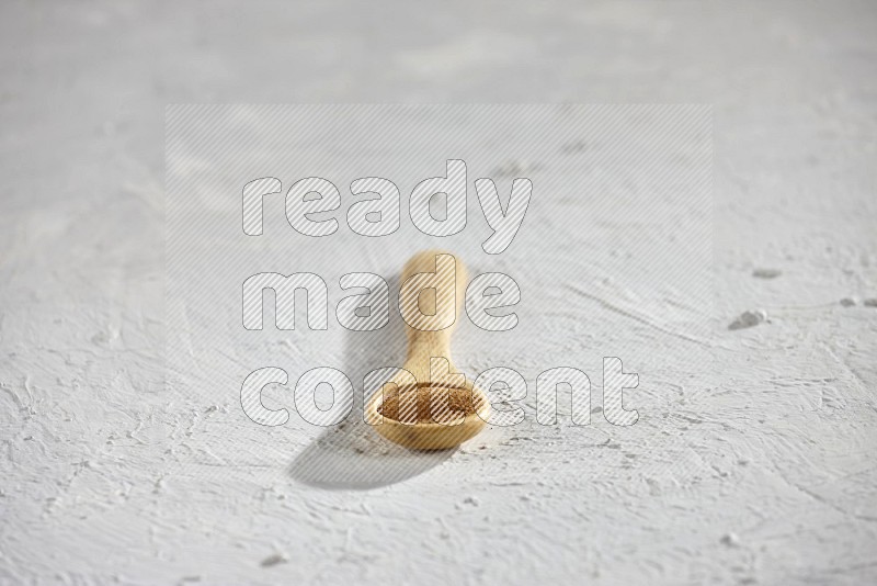 Cinnamon powder in a wooden spoon on a white background