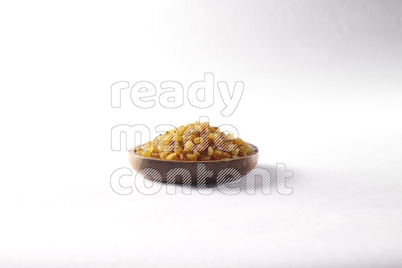 Raisins in a wooden bowl on white background