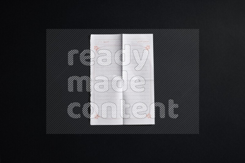 Folded notebook sheet on black background