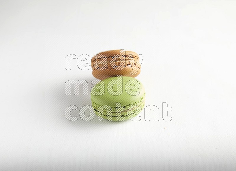 45º Shot of of two assorted Brown Irish Cream, and Green Pistachio macarons on white background